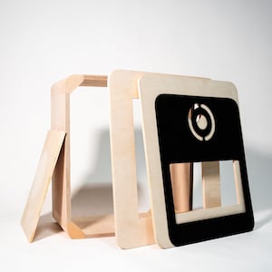 May include: A wooden box with a black front panel and a circular cutout. The box is disassembled, showing the individual pieces.