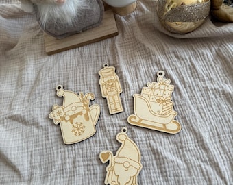 Könnte beinhalten: Helle Holz-Weihnachtsornamente in verschiedenen Formen: ein Wichtel, eine Tasse mit Schneeflocke, ein Nussknacker und ein Schlitten mit Geschenken. Die Ornamente haben ein Loch zum Aufhängen. Weitere Weihnachtsdekorationen im Hintergrund.