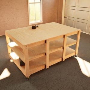 Puede incluir: Un banco de trabajo grande de madera clara con tres estantes y una parte superior plana. El banco de trabajo tiene forma rectangular y está soportado por cuatro patas con ruedas. Una pequeña herramienta está en la superficie superior.