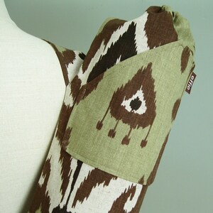 May include: A green and brown yoga mat carrier with a large pocket and the word "enjie" printed on the side.