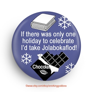 May include: A purple button with a white snowflake, a book, and a broken chocolate bar with the text "Chocolat" on it. The text on the button reads "If there was only one holiday to celebrate I'd take Jolabokaflod!"