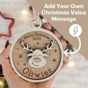 May include: A round wooden Christmas ornament with a reindeer design, the words "Merry Christmas 2024" and the name "Oliwier".