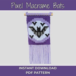 May include: A macrame wall hanging with a pixelated bat design in purple, white, and grey. The artwork is mounted on a wooden dowel and has long fringe. The text at the top reads "Pixel Macrame Bats".