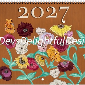 May include: A 2027 wall calendar with a spiral binding at the top, featuring a brown background decorated with a colorful painted floral pattern. The text DevsDelightfulDesign is printed in white across the center of the floral arrangement.