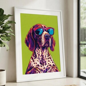 May include: A framed wall art print featuring a stylized illustration of a spotted dog wearing bright red sunglasses with blue lenses. The dog has purple and orange fur tones set against a solid lime green background within a white frame.