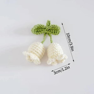 May include: Crocheted white flower buds with a green leaf, measuring 3.9 inches in height and 1.2 inches in width. The handmade floral design features a textured stitch, perfect for crafts and embellishments.