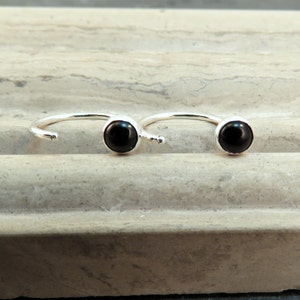 May include: A pair of silver hoop earrings with black gemstone accents.