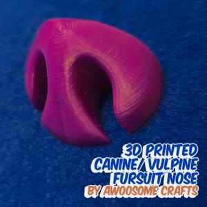May include: A 3D printed purple faux fursuit nose. The nose is designed for a canine or vulpine character. The text "3D PRINTED CANINE/VULPINE FURSUIT NOSE BY AWOOOSOME CRAFTS" is printed below the nose.