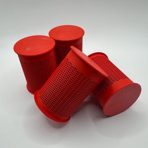 May include: Four red plastic hair rollers with a grid pattern. The rollers are stacked on top of each other.