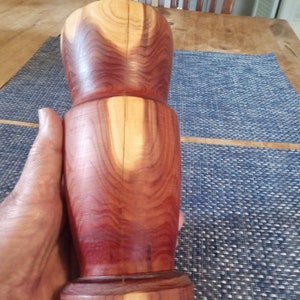 Può includere: Un vaso di legno di colore marrone rossiccio con un motivo a venature di legno naturale. Il vaso ha un'apertura larga e una base stretta.