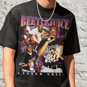 May include: A black t-shirt with a graphic print of a group of people, including the text "Beetlejuice" and "Lester Greef".