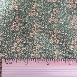 Puede incluir: Primer plano de una tela verde con un estampado floral en un color beige más claro. La tela es texturizada y tiene una regla con pulgadas marcadas a lo largo del borde superior. La regla muestra medidas de hasta 7,6 cm.