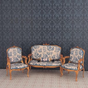 May include: Miniature antique furniture set featuring a loveseat and two armchairs. The wooden frames are gold-toned, with blue and white patterned upholstery. The set is arranged on a patterned floor against a dark blue damask wallpaper background.