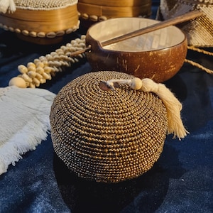 Peut inclure: Diverses boîtes et bols décoratifs. Les boîtes rondes sont recouvertes de perles dorées, avec un pompon. Un bol en noix de coco avec une cuillère en bois est également visible, ainsi qu'une guirlande de coquillages.