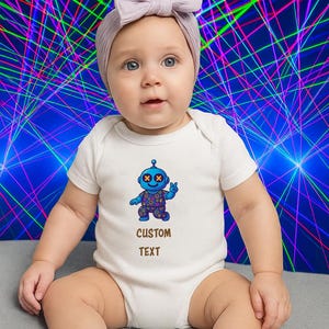 May include: A baby wearing a white onesie with a blue robot graphic and the text "CUSTOM TEXT". The baby is also wearing a light purple bow headband. The background features a colorful, abstract design.