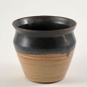 May include: A ceramic pot with a dark brown glaze on the top half and a light brown glaze on the bottom half.