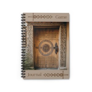 May include: A brown spiral bound journal with a wooden door with intricate carvings and a metal handle. The cover has the text "Game" at the top and "Journal" at the bottom.