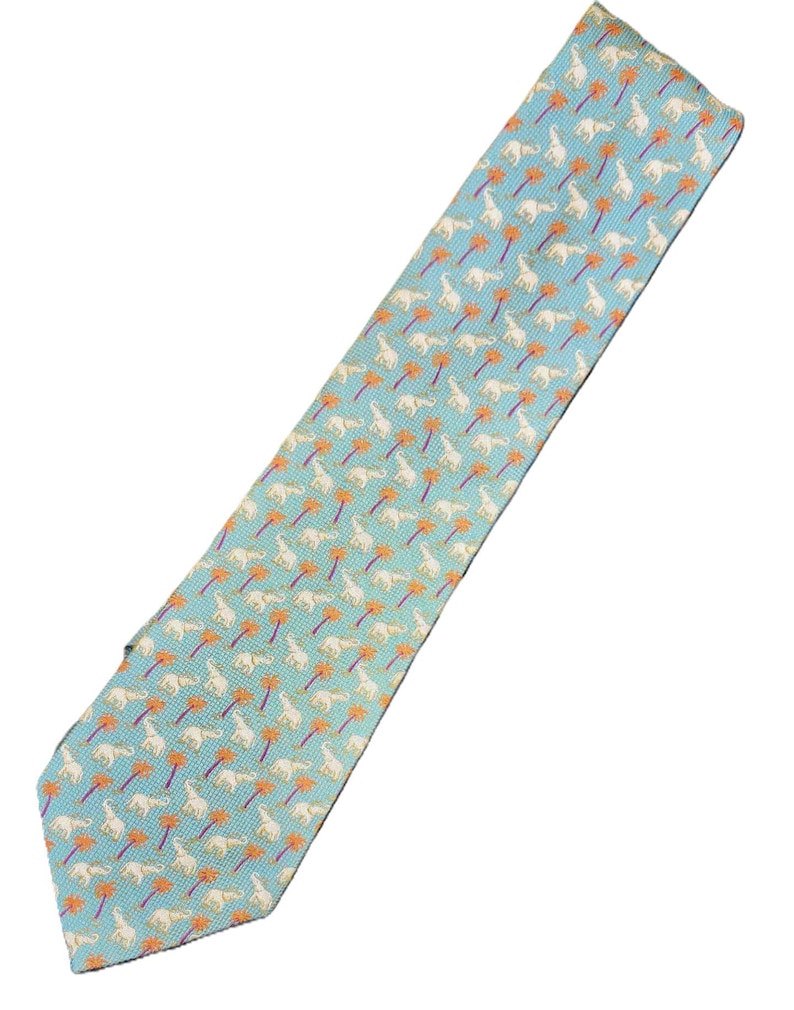 May include: A light blue necktie with a repeating pattern of white elephants and orange palm trees. The tie is made of a smooth fabric and has a classic pointed end.