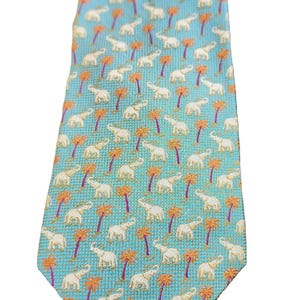 May include: A light blue necktie with a repeating pattern of white elephants and orange palm trees. The tie has a textured appearance and a classic pointed end. A stylish accessory for any wardrobe.