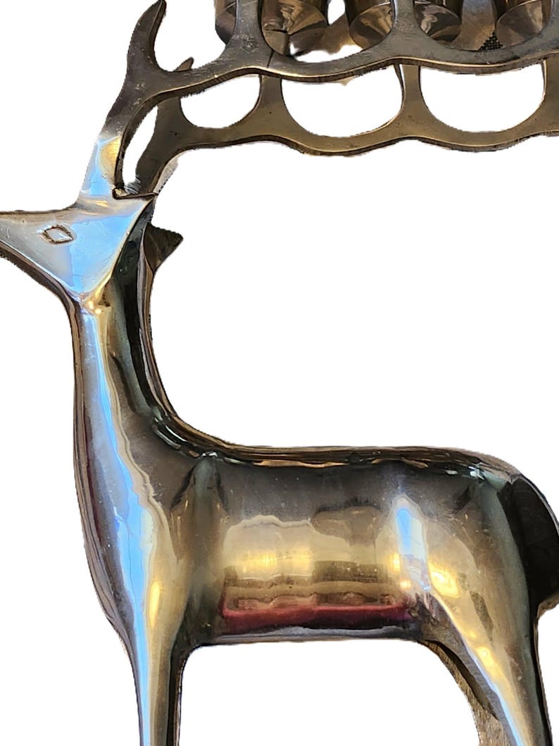May include: A polished brass deer sculpture with a rack of antlers. The deer has a sleek, reflective surface and a detailed design. The sculpture is a decorative item, suitable for home decor.