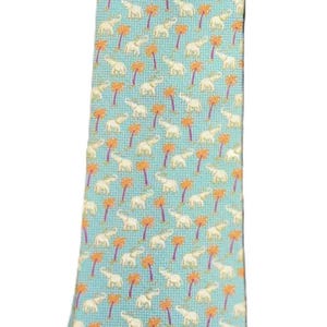 May include: A light blue necktie with a repeating pattern of white elephants and orange palm trees. The tie is a standard length and width, suitable for formal or business attire.