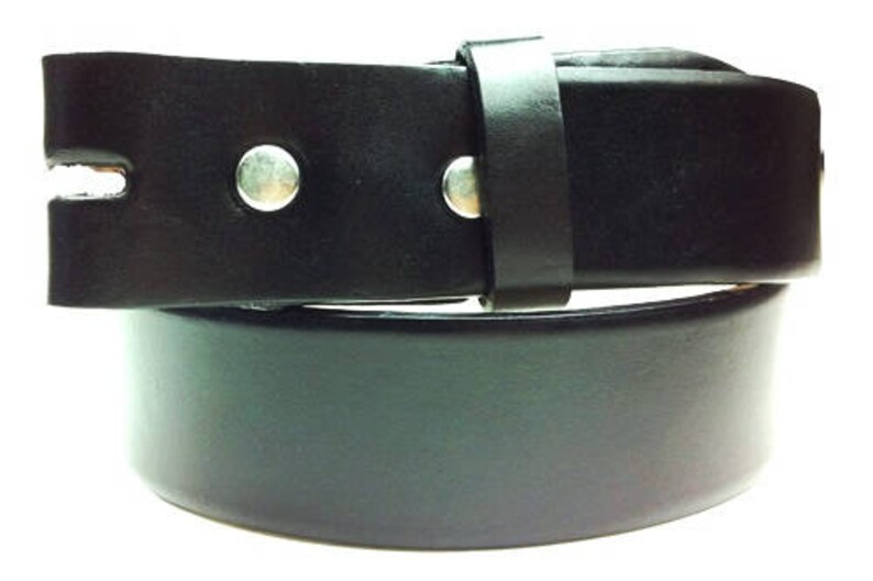 Puede incluir: Un cintur&oacute;n de cuero negro con una hebilla plateada y dos remaches plateados. El cintur&oacute;n est&aacute; doblado por la mitad, mostrando el interior del cuero.