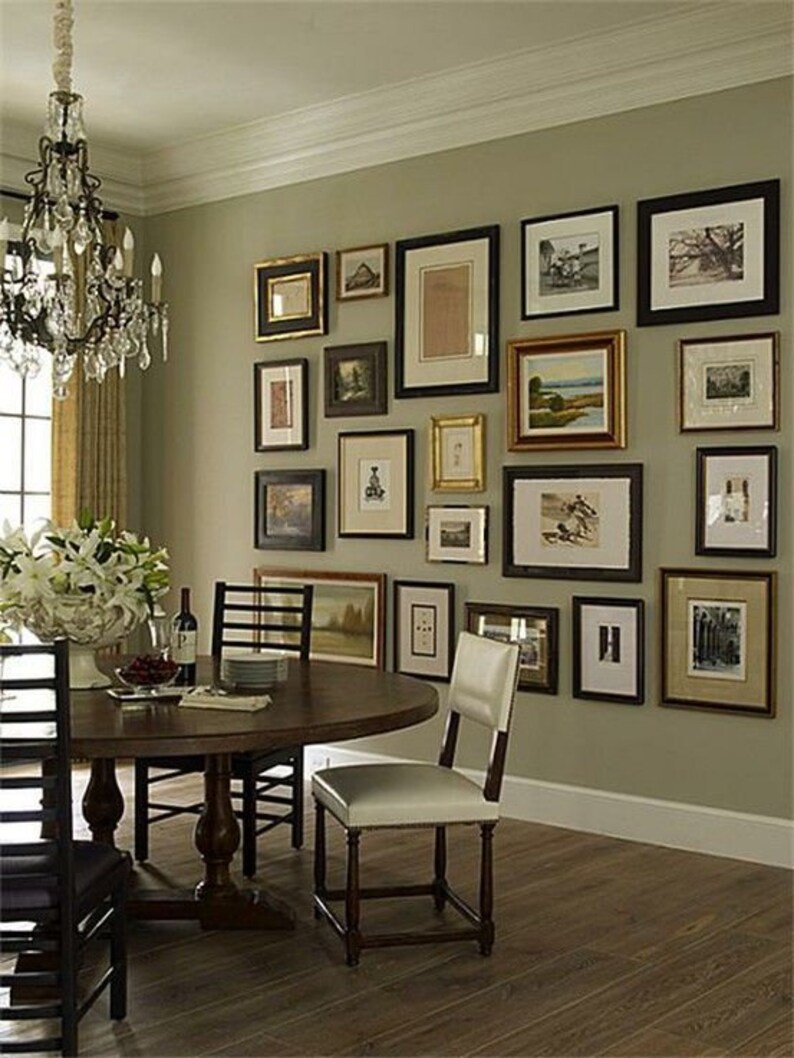 May include: A dining room with a round wooden table and chairs. The wall is decorated with a gallery wall of framed artwork in various sizes and styles.