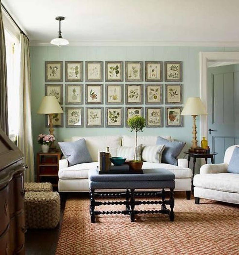 A symmetrical gallery-style display on a light blue or light green wall above a couch. Twenty-one botanical prints in matching frames arranged in three long rows.