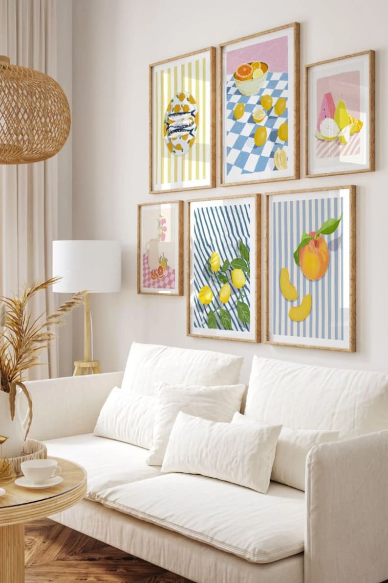 May include: A set of six framed prints featuring various still life arrangements of fruit, including lemons, peaches, and watermelon. The prints are all in a similar style, with a white background and colorful stripes. The frames are all wooden and have a natural finish.