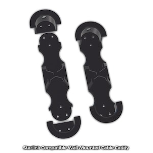 May include: Two black plastic wall-mounted cable caddies designed to hold Starlink cables. The caddies have a unique design with a curved top and bottom and a central section with a cutout for cable management.