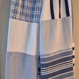 Peut inclure: Pantalon large composé de divers panneaux en tissu éponge bleu et blanc. Le vêtement présente un mélange de motifs incluant des carreaux, des rayures verticales et des rayures horizontales, avec une taille élastique et une coupe ample.