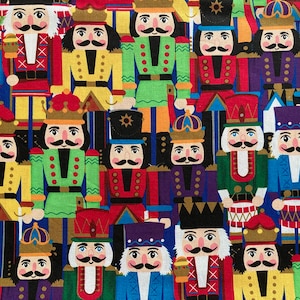 Könnte beinhalten: Ein farbenfroher Stoff mit einem sich wiederholenden Muster von Nussknacker-Soldaten. Die Nussknacker tragen unterschiedlich farbige Uniformen und Hüte, und einige halten Trommeln, Schwerter und anderes Zubehör.