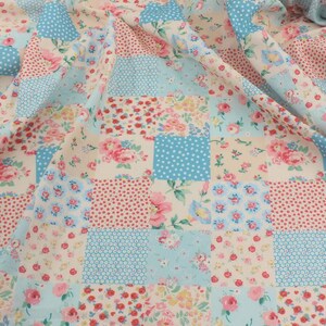 May include: A patchwork fabric with a floral pattern in pink, red, and blue. The fabric is composed of squares with various designs, including polka dots and floral prints. The overall color scheme is pastel, with a vintage aesthetic.