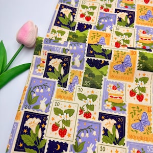 May include: Fabric with a repeating pattern of postage stamp designs. The stamps feature illustrations of flowers, strawberries, butterflies, and landscapes in shades of purple, yellow, and green. The word "MOONBERRY" is visible on some stamps.