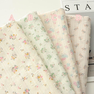 May include: Four rolls of floral fabric in cream, white, and pastel colours. Each fabric has a different floral pattern with pink, yellow, and blue flowers. The fabrics are arranged side by side, with the letters A, B, C, and D marking each roll.