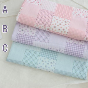 May include: Three folded patchwork fabric samples in pink, lavender, and blue. Each fabric features a variety of patterns, including floral prints, gingham checks, and polka dots. The fabrics are arranged in a layered composition.