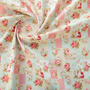 Könnte beinhalten: Ein rosa-weißer Blumenstoff mit Patchwork-Muster. Der Stoff zeigt verschiedene rosa Rosen und andere Blumen auf weißem Hintergrund. Der Stoff ist perfekt zum Quilten, Basteln und für andere Nähprojekte.