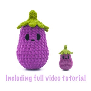Puede incluir: Dos berenjenas de ganchillo, una grande y otra pequeña, en tonos morados con copas verdes. Las berenjenas tienen ojos negros y caras sonrientes. El texto "Including full video tutorial" está en la parte inferior.