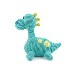 May include: A crocheted turquoise dinosaur toy with yellow spots and a green spiky back.