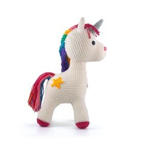 May include: A crocheted unicorn toy in off-white with a rainbow mane and tail. The unicorn has a gray horn, a pink nose, and a yellow star on its side. The hooves are a deep pink color. This handmade toy is perfect for children.
