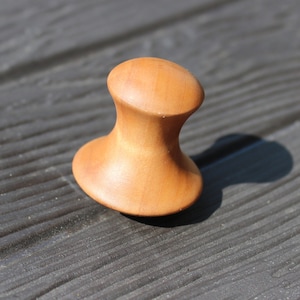 May include: A wooden knob with a rounded top and a wider base. The knob is light brown in color and has a smooth, polished finish.