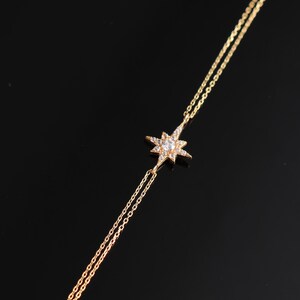 May include: A gold chain bracelet with a star-shaped charm set with clear cubic zirconia stones.