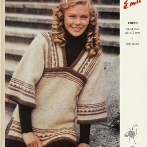 Puede incluir: Una mujer con un suéter de punto beige y marrón con cuello en V y mangas anchas. El suéter tiene patrones geométricos marrones y rayas horizontales. El texto "Emu" y "FIORD" son visibles.