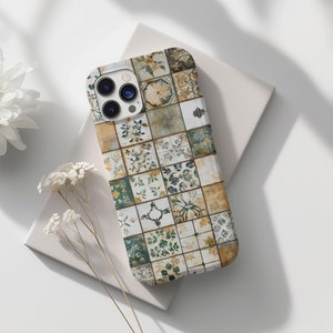 May include: A white iPhone case with a colourful tile pattern featuring green, brown, and white colours. The case has a camera lens cutout and a geometric design.