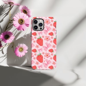 K&ouml;nnte beinhalten: Eine rosa Handyh&uuml;lle mit einem Muster aus Erdbeeren, Blumen und Schleifen. Die H&uuml;lle ist f&uuml;r ein iPhone konzipiert.