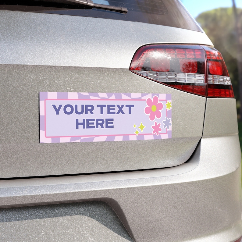 May include: A silver car with a purple and pink bumper sticker that says "YOUR TEXT HERE" with a pink flower and yellow stars.