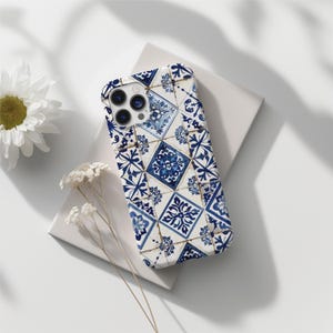 May include: A white iPhone case featuring a blue and white tiled pattern. The case has a camera cutout and a white background.
