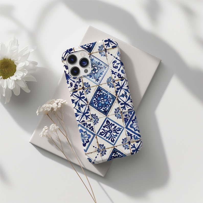 May include: A white iPhone case featuring a blue and white tiled pattern. The case has a camera cutout and a white background.