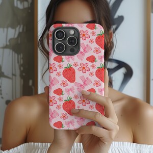 K&ouml;nnte beinhalten: Eine rosa Handyh&uuml;lle mit einem Muster aus Erdbeeren und Schleifen. Die H&uuml;lle ist f&uuml;r ein iPhone 13 Pro Max konzipiert.