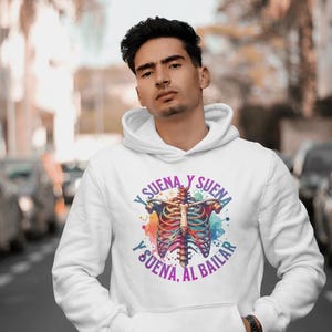 May include: White hoodie with a colorful anatomical heart graphic and the text "Y suena y suena y suena, al bailar" printed on the front.